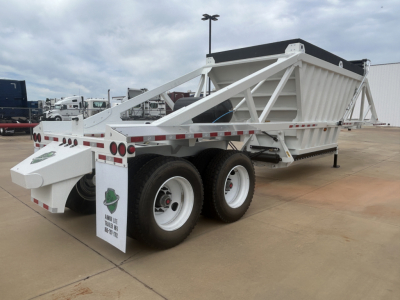 Trailer with white dump body and dual rear axles showing Armor Lite branding on rear mudflaps and reflective tape along sides; side railings and triangular support frame visible.