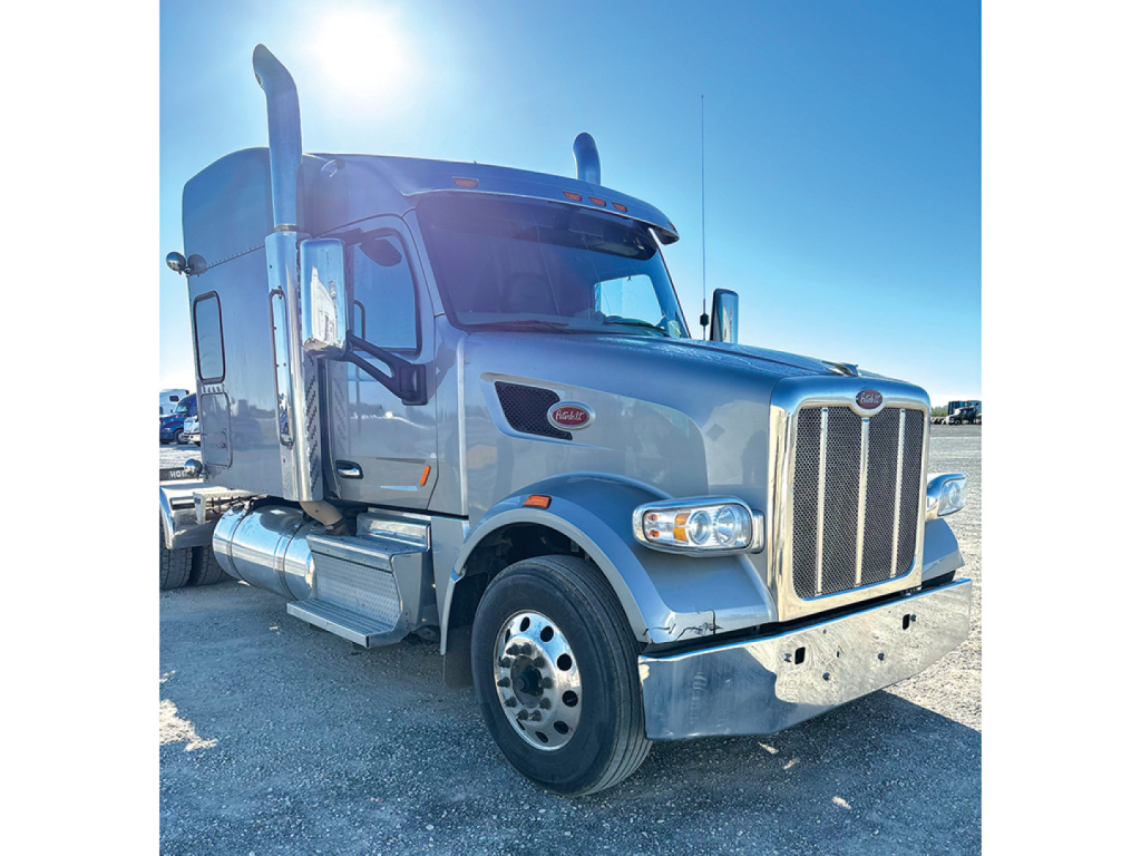 Peterbilt 567 UltraCab aftermarket truck front three-quarter view showing chrome grille, large fuel tanks, and dual exhaust stacks.