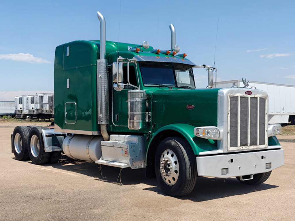 Peterbilt 389 UltraCab Extended Hood semi-truck in green with chrome accents, front grille, tall exhaust stacks, and sleeper cab; three rear axles visible.