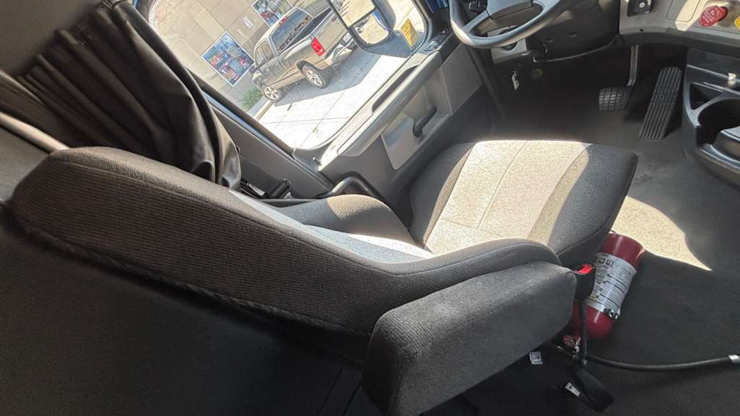 Cab interior of a Freightliner PT126064ST truck showing driver seat, passenger seat, and mounted fire extinguisher.