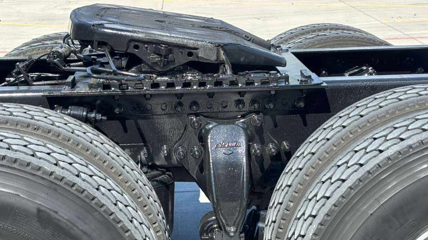 Tractor-trailer truck chassis with fifth wheel and dual rear axles, visible are frame rails, suspension, and drive components.