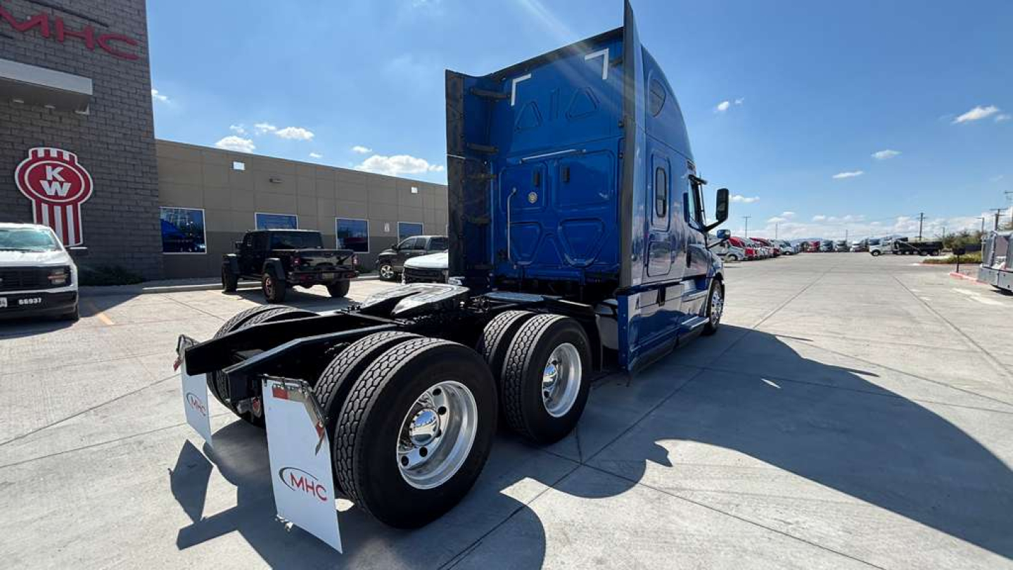 Truck tractor in blue with sleeper cab, rear view showing dual rear axles and fifth wheel, Freightliner PT126064ST unknown text on mudflaps