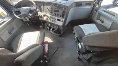 Cab interior of a 2022 Freightliner PT126064ST showing steering wheel, dashboard with controls, center console, and two seats with a fire extinguisher on the floor.