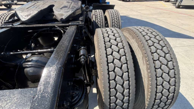 Dual rear wheels and undercarriage of a Freightliner tractor showing tandem axle suspension and tires.