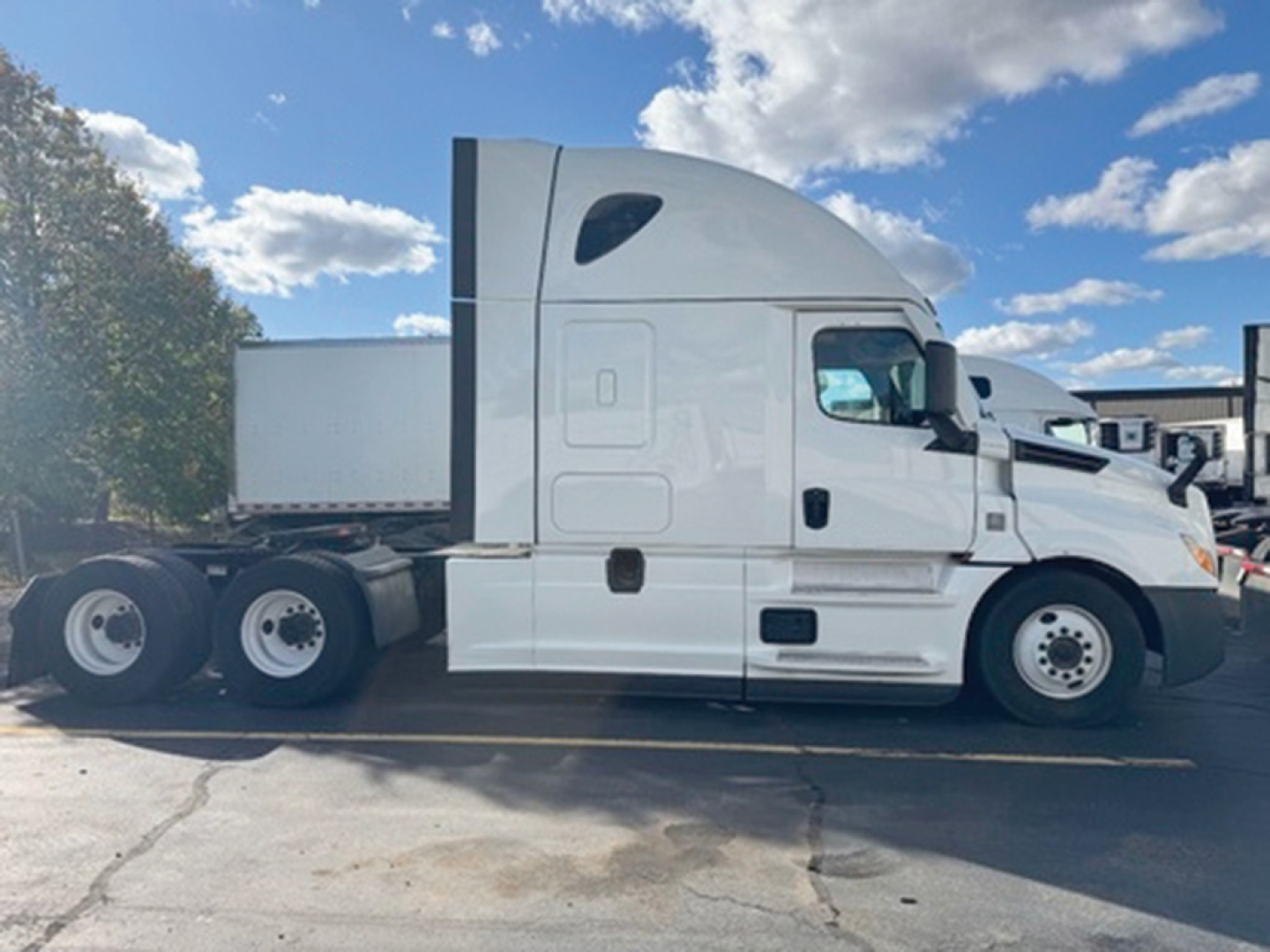 Freightliner Cascadia126 sleeper tractor in side profile showing tractor cab, sleeper, and rear axles under a blue sky.