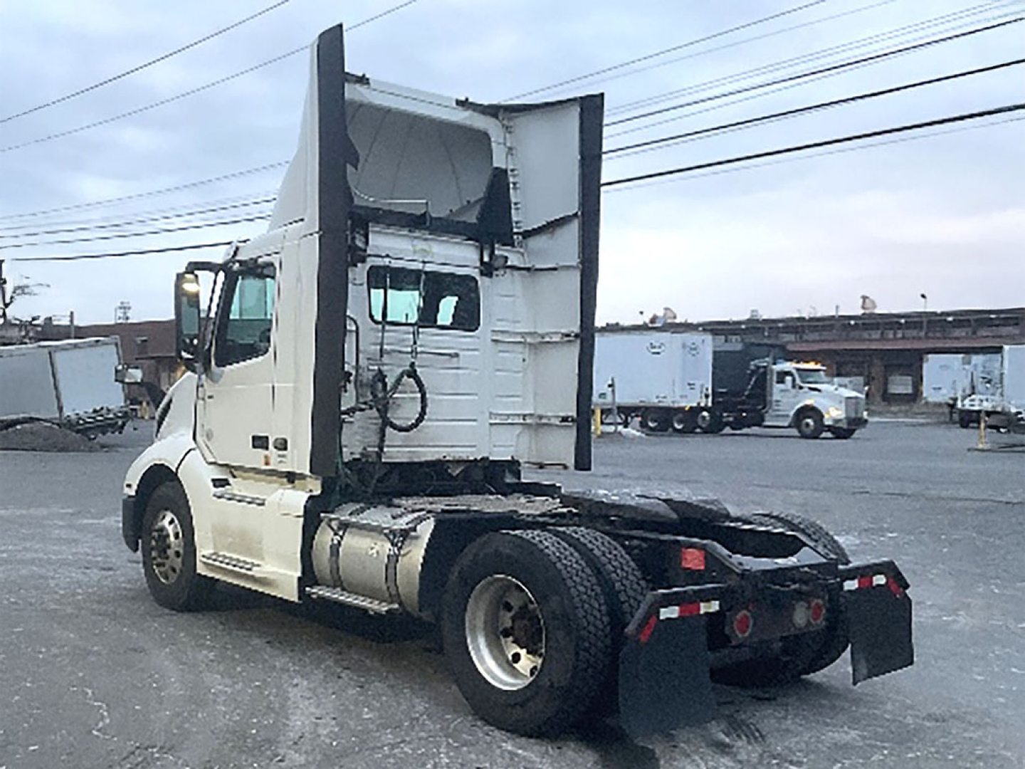 Volvo VNR 300 conventional daycab tractor rear view showing chassis and rear fenders with mud flaps and fuel tanks.