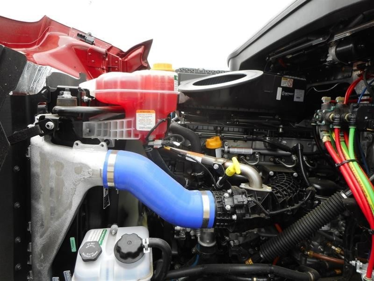 Western Star 47X engine bay showing blue silicone intake hose, coolant reservoir, yellow-handled dipstick, and electrical harnesses.
