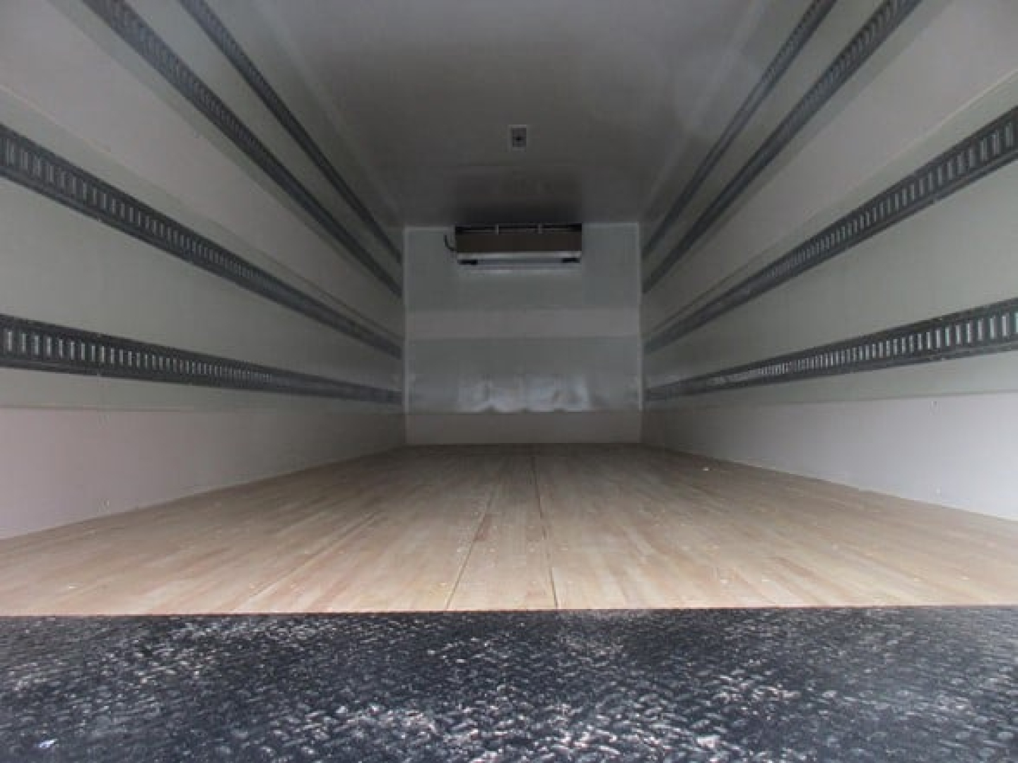 Freightliner M2 106 Plus refrigerated truck cargo area interior. Empty trailer with wood floor and aluminum side rails.