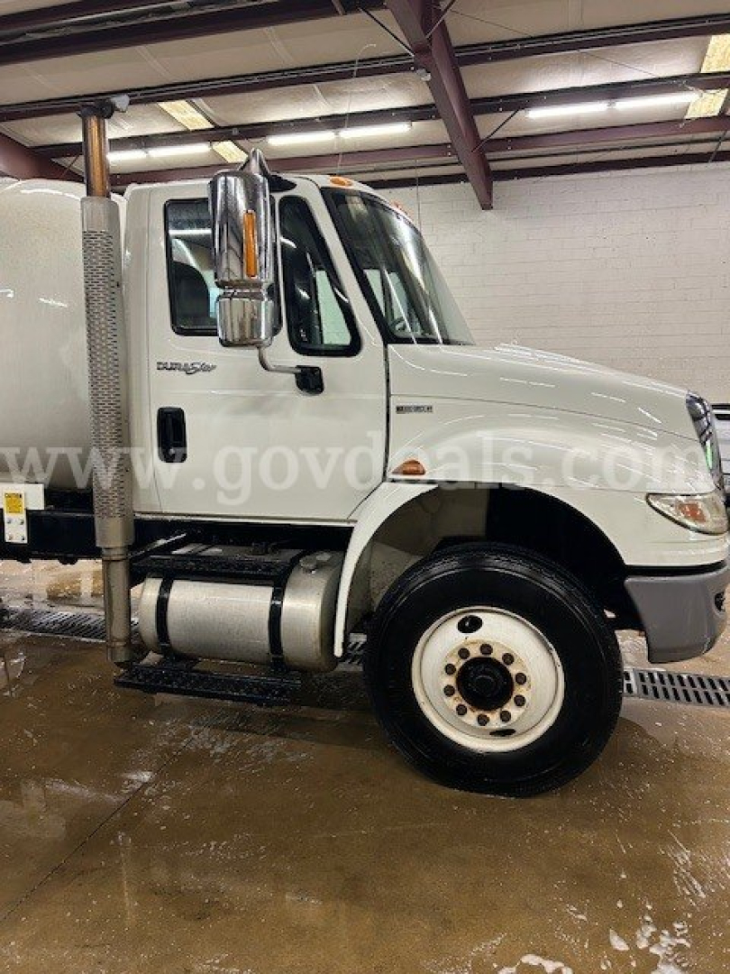 International 4300 truck cab in shop showing side view with fuel tank and wheels.