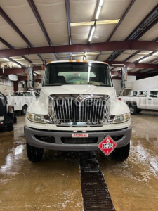 Truck front view of a white 2011 International 4300 tanker in a showroom, with large chrome grille, propane diamond label 1075, and stock plate 12194-13.