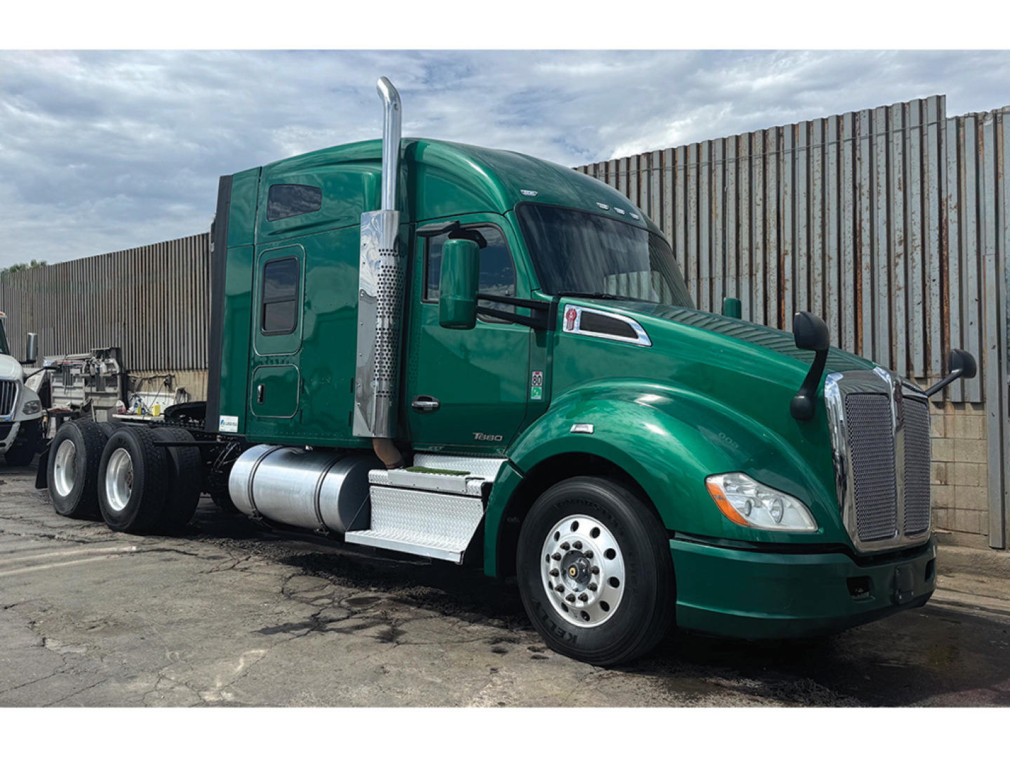 Kenworth T680 2019 conventional sleeper tractor, green, side view showing cab with chrome exhaust stack and fuel tanks.