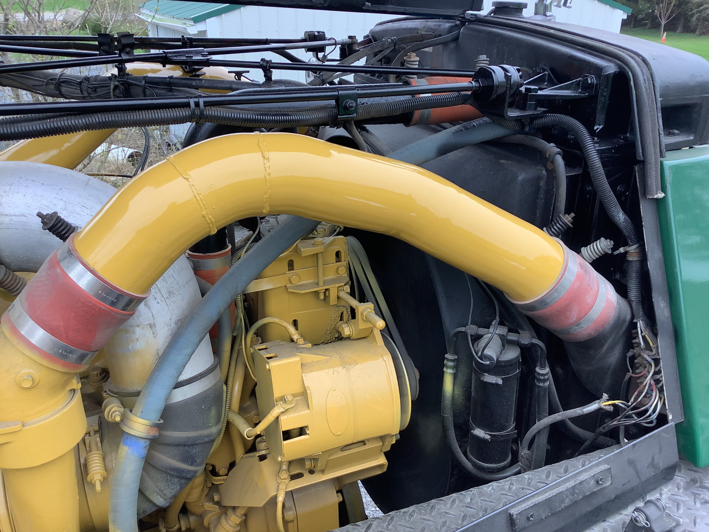 Mack RD8 engine bay with yellow turbo/intercooler pipes and hose fittings visible in a green truck.