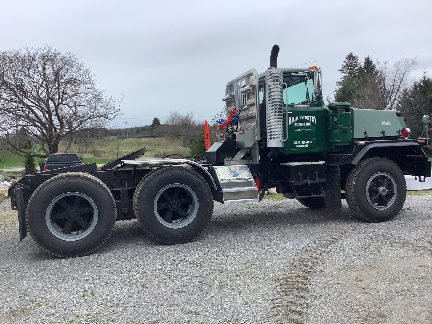 Mack RD8 tractor with green cab and aluminum fuel tanks, side view showing dual rear axles and fifth-wheel area.