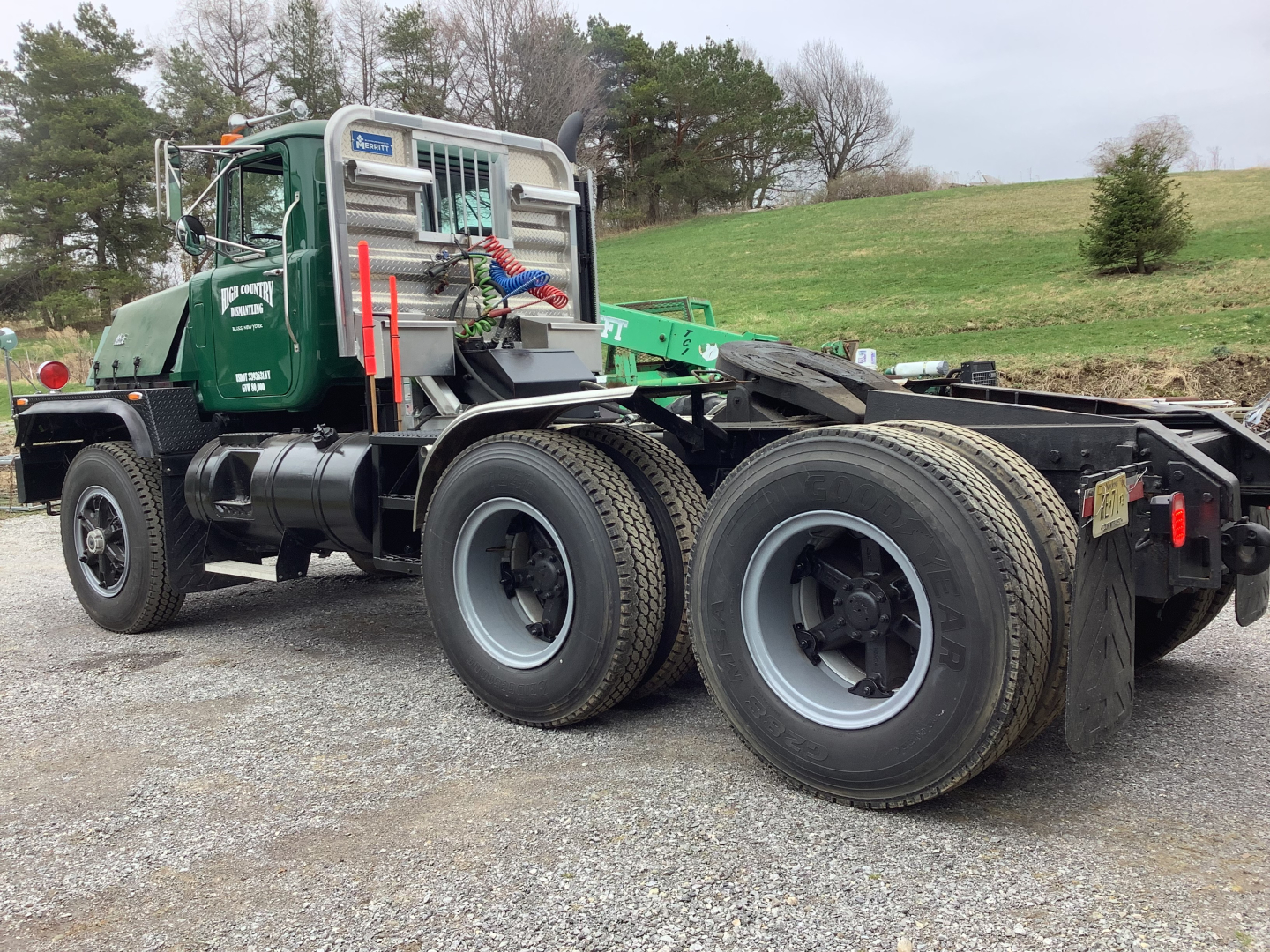 Mack RD8 tractor unit in green with dual rear axles and grey wheels, side view showing cab, exhaust, and fifth-wheel area.