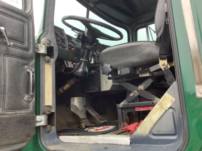 Cab interior of a 1994 Mack RD8 truck showing steering wheel, dashboard, driver's seat, and entry door area.