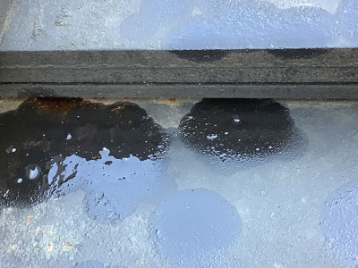 Partial exterior view of a 1994 Mack RD8 truck showing a blue surface with black paint splashes and a rubber seal/gasket edge.
