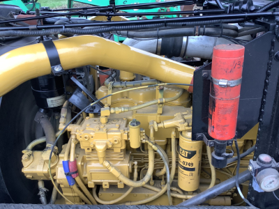 Mack RD8 engine bay showing diesel engine with yellow paint and hoses, large curved yellow intake, red cylindrical filter canister, and CAT tag label.