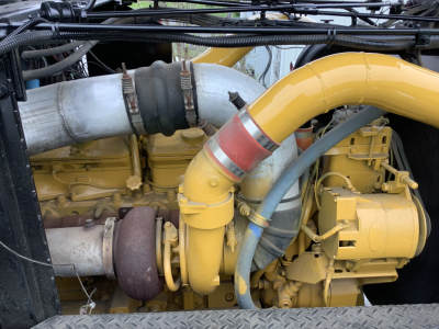 Mack RD8 engine bay showing large yellow turbocharger and intercooler piping with metal hose clamps and hoses visible.