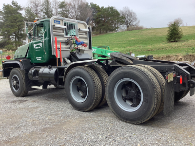 Mack RD8 tractor unit in green with dual rear axles and grey wheels, side view showing cab, exhaust, and fifth-wheel area.