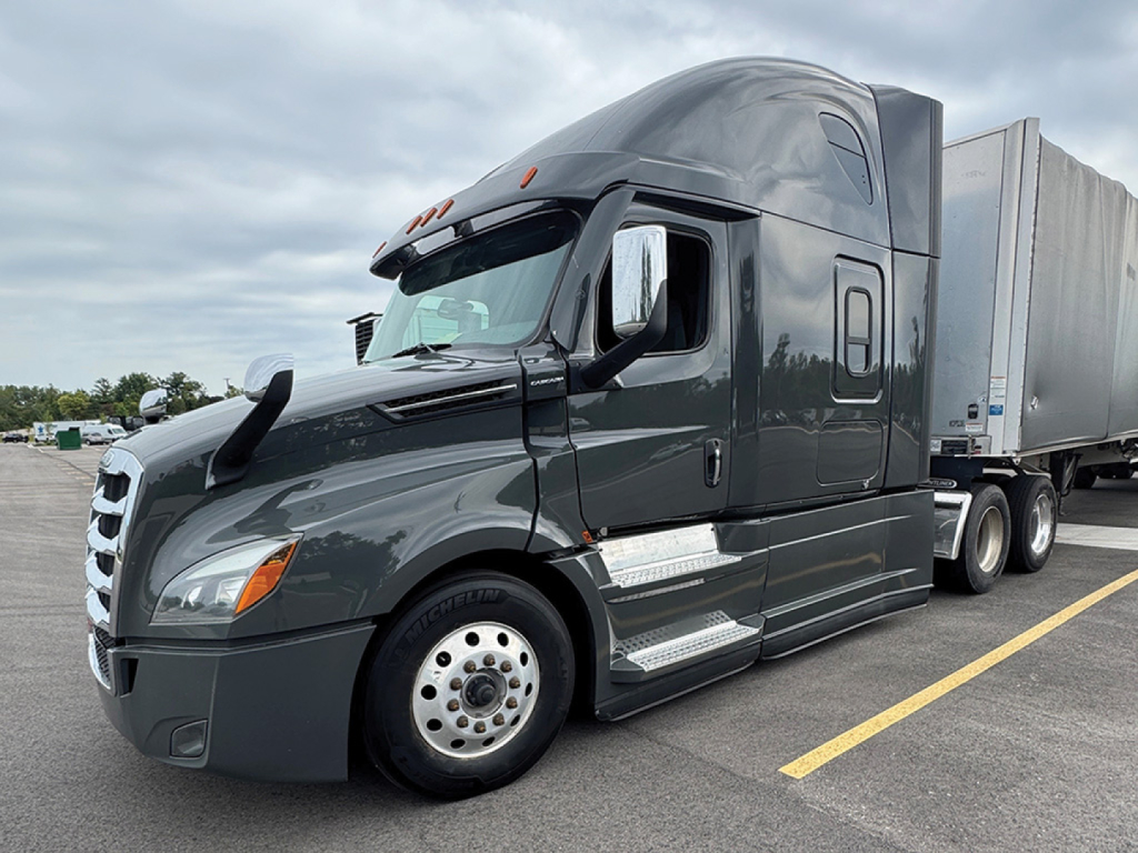 Tractor truck cab in a parking lot showing 2023 Freightliner Cascadia126 with sleeper, side steps, and attached trailer.