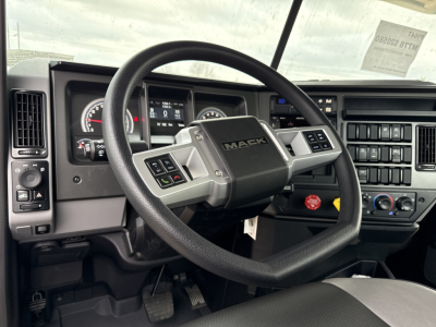 Mack PI64T truck cockpit showing steering wheel and dashboard with gauges and controls.