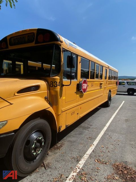School bus side view showing yellow body, stop sign extended, bus number 834, front wheel, and windows. Visible lettering near roof warns 'SCHOOL BUS'.