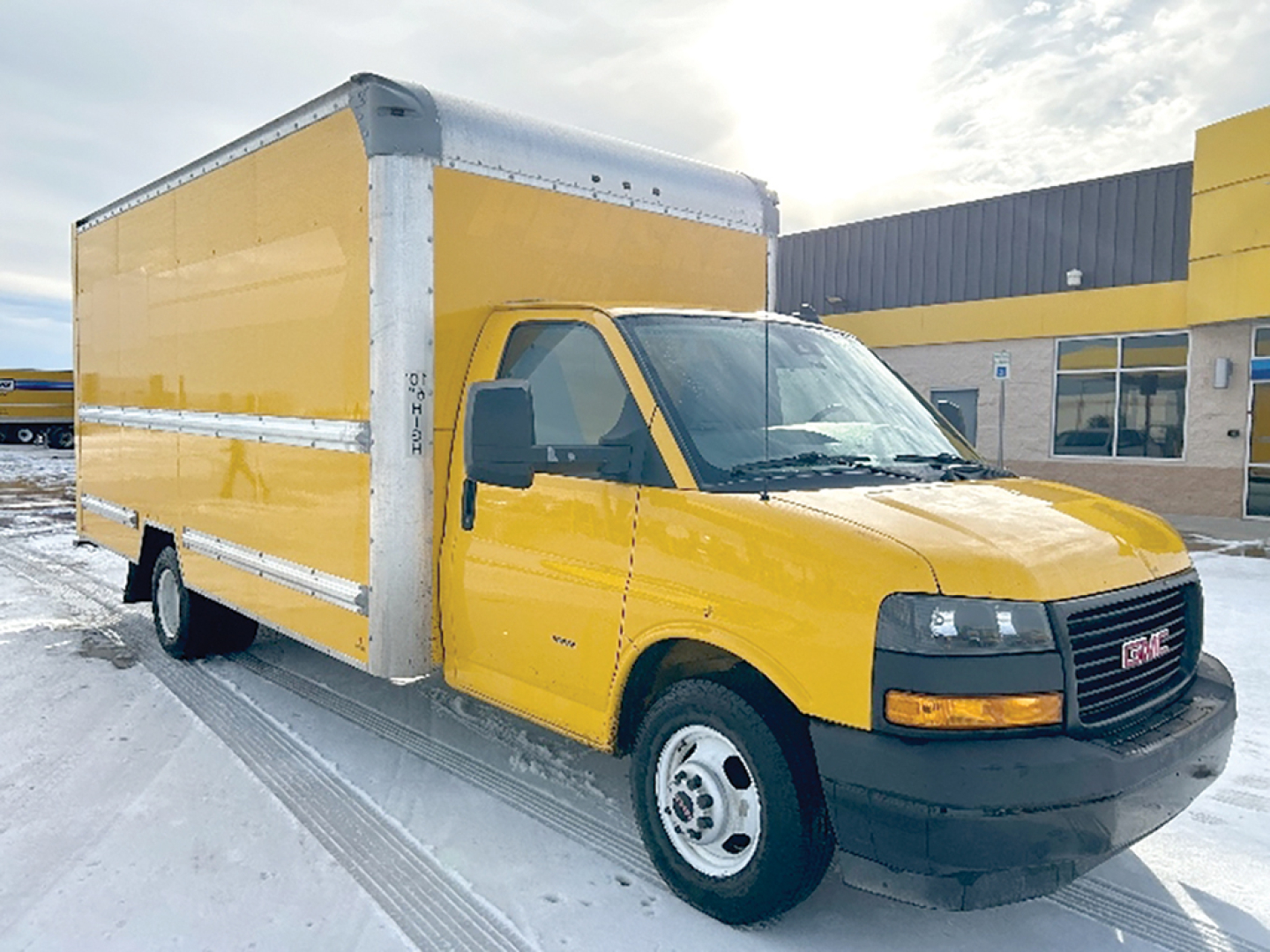 GMC Savana box truck in yellow with cargo box on chassis, side view showing cab and box, VIN and stock not visible on image but vehicle identified.