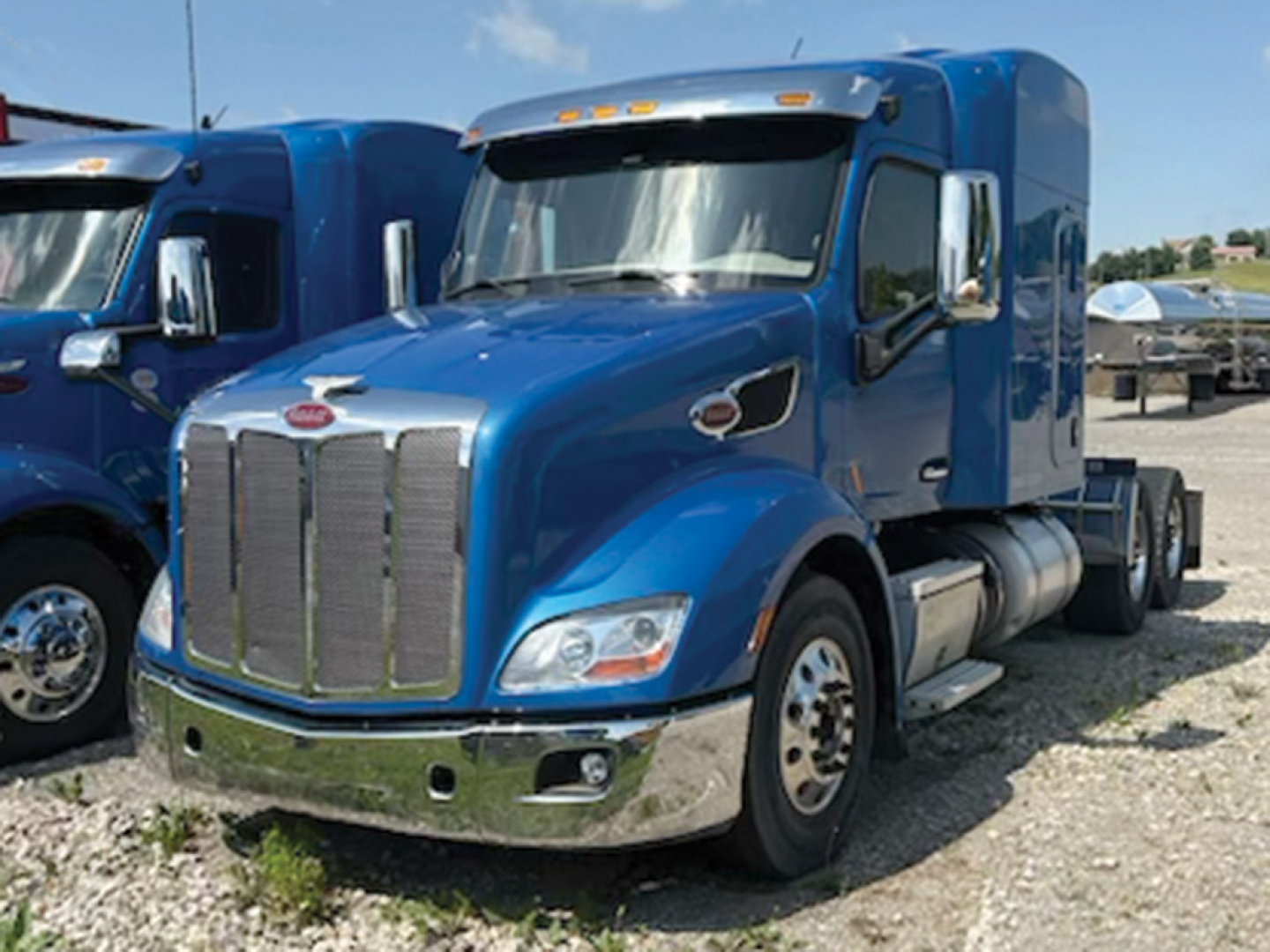 Peterbilt 579 UltraCab semi truck in blue, front three-quarter view showing chrome grille, bumper, and dual fuel tanks.