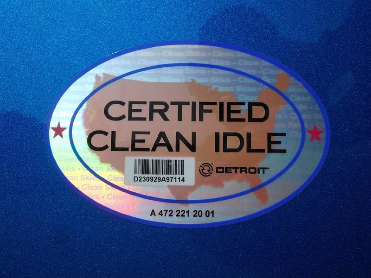 Truck badge showing CERTIFIED CLEAN IDLE oval sticker on blue paint surface.