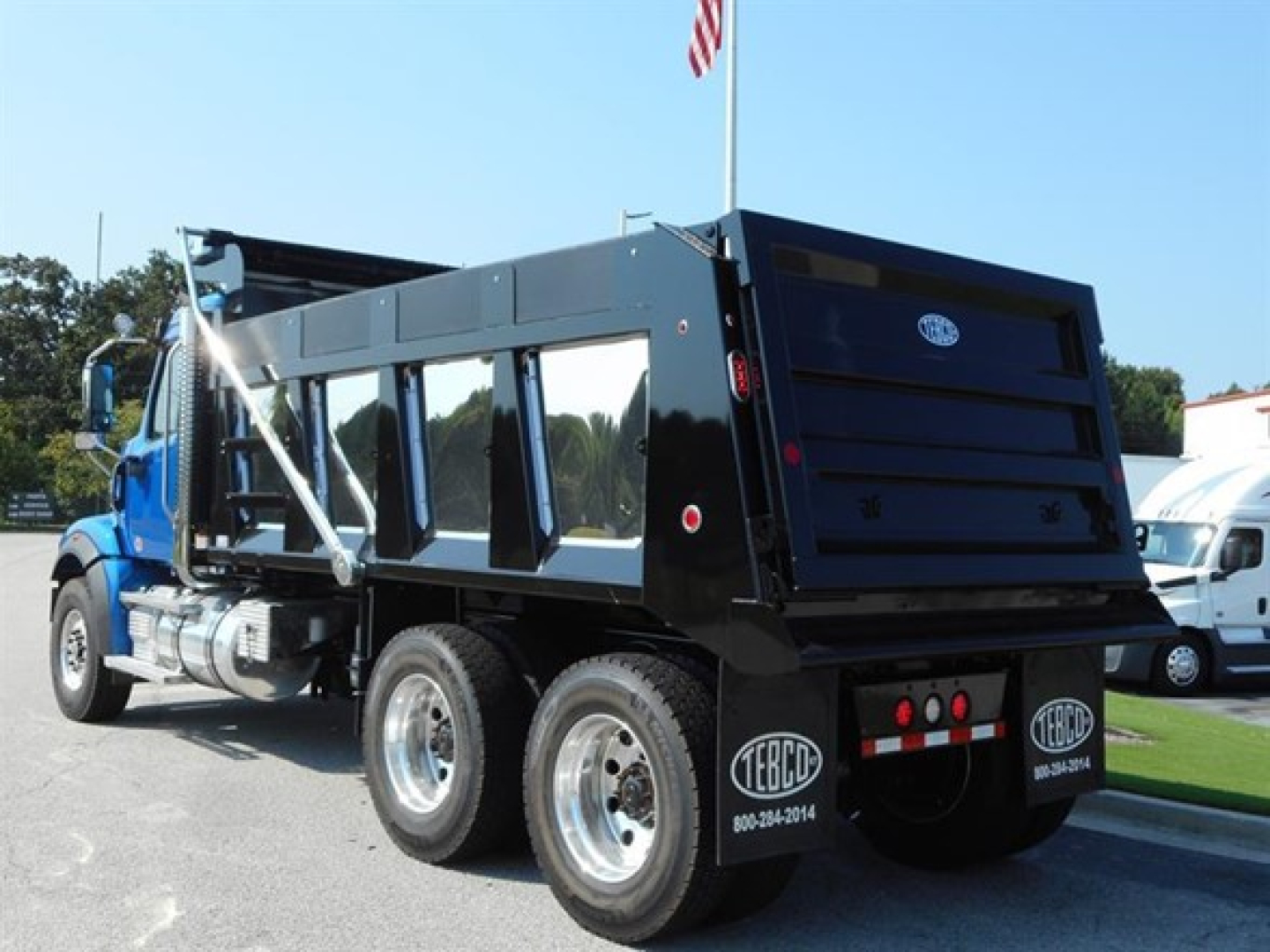 Western Star 47x dump truck in serviceable condition with black dump bed and dual rear axles, side mirrors, and reflective decals.