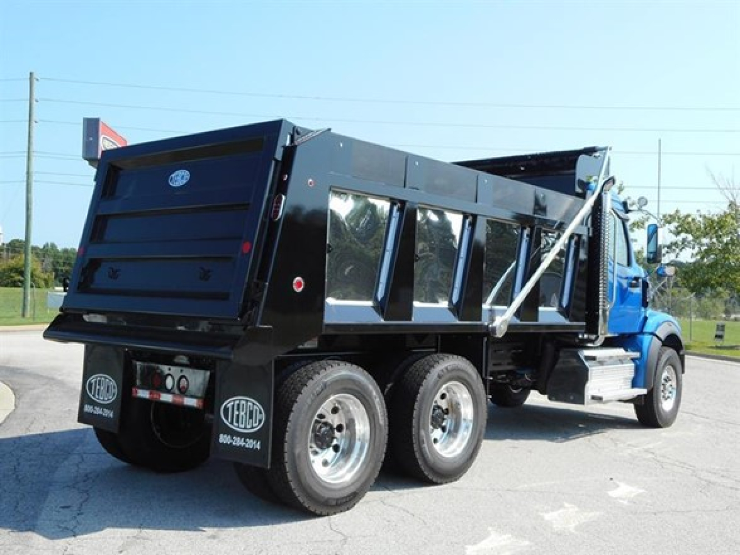Dump truck rear and side view showing heavy-duty dump body with dual rear axles, side panels, and Terex/Western Star branding. Visible features include black dump bed, tailgate, rear bumper, and tires.