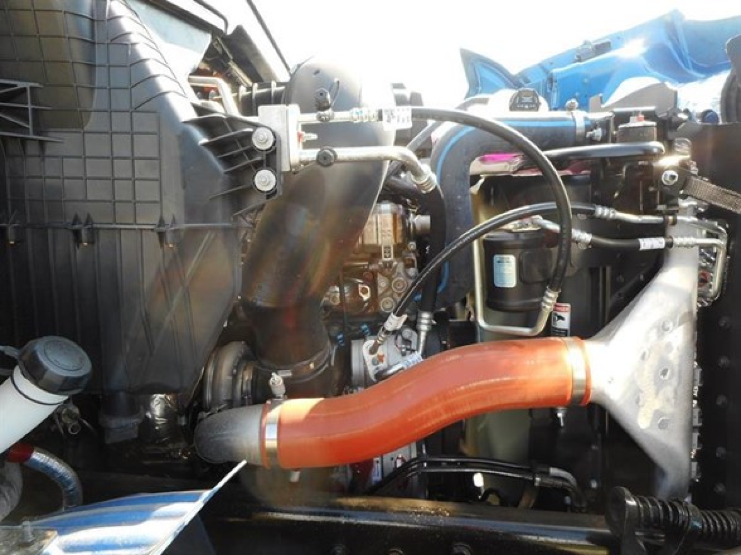 Western Star 47x engine bay showing orange coolant hose and various hoses, radiator, and components visible in front side of engine compartment.