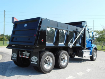 Dump truck rear and side view showing heavy-duty dump body with dual rear axles, side panels, and Terex/Western Star branding. Visible features include black dump bed, tailgate, rear bumper, and tires.