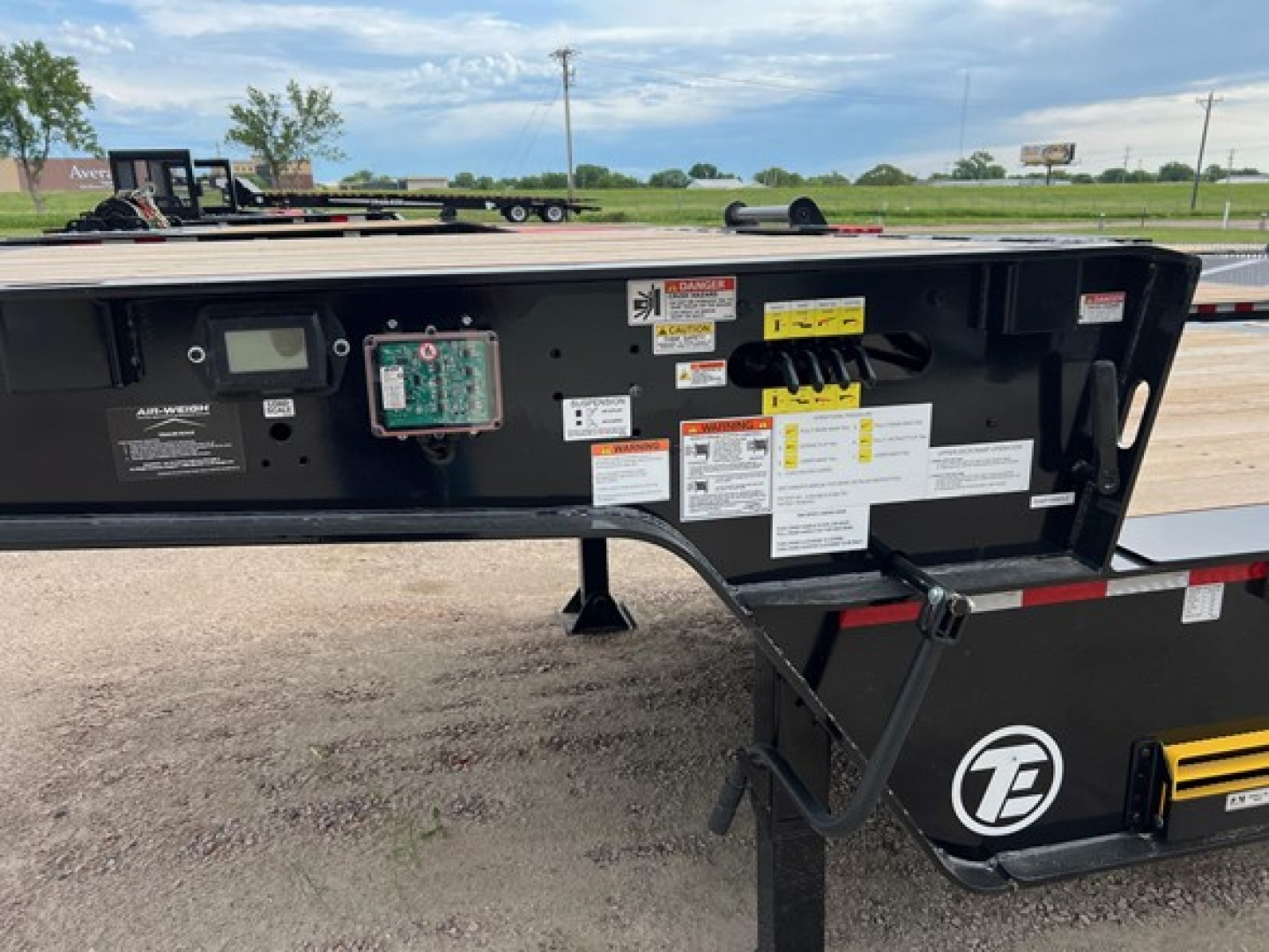 Teal Trail-Eze TE80HT trailer chassis view showing control panel, warning labels, and electrical box with labels and wiring.