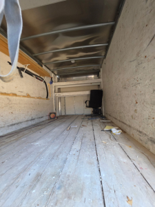 Truck cargo area of a 2016 Chevrolet Express 3500 box truck showing interior walls, floor, and a chair at the far end.