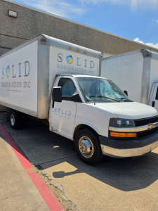 Box truck with SOLID Restoration Inc. branding on cargo box and cab, Chevrolet logo on front grille, side mirrors, and SOLID lettering on the box.