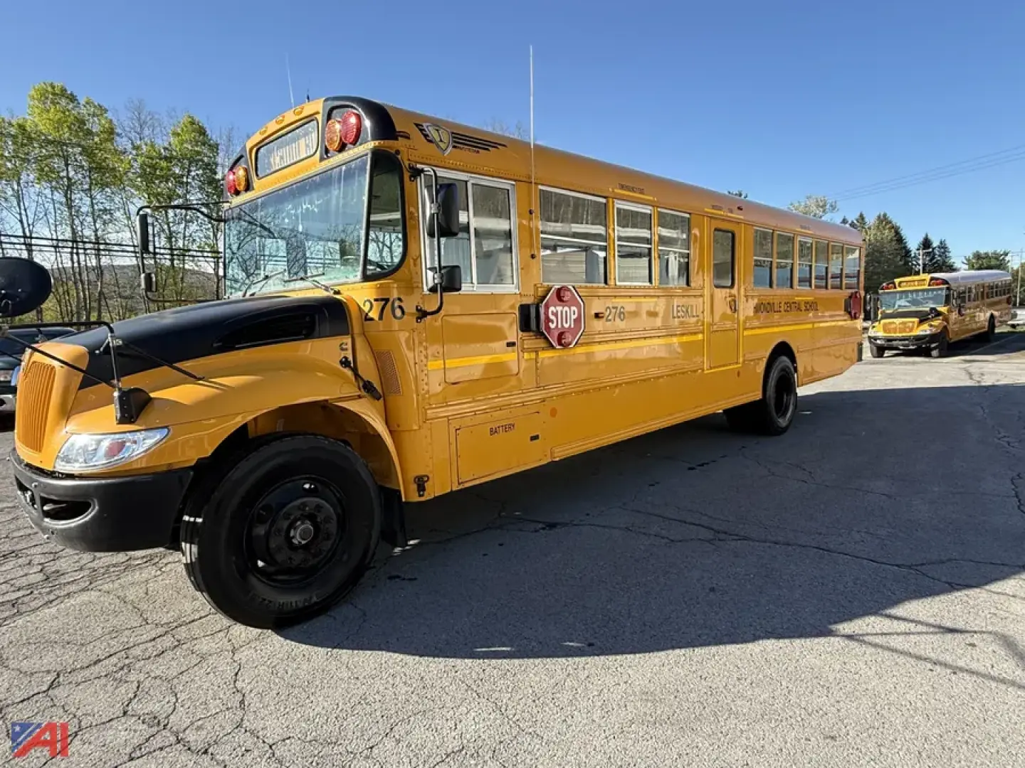 IC Corporation CE Series school bus with stop sign out and chrome wheels, yellow body, front view on a parking lot.