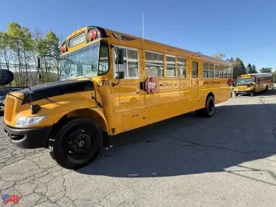 IC Corporation CE Series school bus with stop sign out and chrome wheels, yellow body, front view on a parking lot.