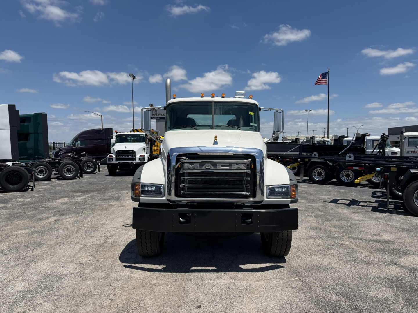 Front view of a white 2025 Mack GR64F cab and chassis truck showing the Mack grille, bumper, and headlights.