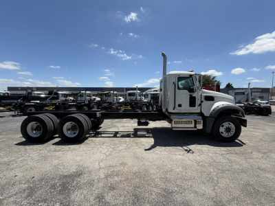 New 2025 Mack GR64F cab and chassis truck side view showing long frame and dual rear axles with white cab and chassis greens.