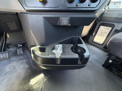 Cab interior view of a 2025 Mack GR64F showing a center dash area with a cup holder/ashtray and a small storage slot.