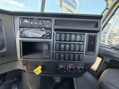 Dashboard of 2025 Mack GR64F cab and chassis showing steering area with gear selector buttons (R N D M), switch panel, climate controls, and ignition key slot.