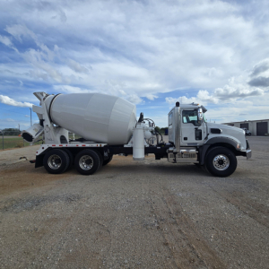 Mixer truck in side view showing concrete mixer drum and chassis with cab at right, blue sky with clouds.