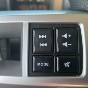 Cockpit control panel of a Mack GR64B mixer showing audio/volume buttons, mode button, and mute button.