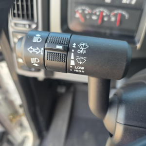 Left-side stalk in a Mack GR64B truck showing control symbols for headlights, turn signals, and wiper settings including OFF, LOW, HIGH, and windshield wiper icons.
