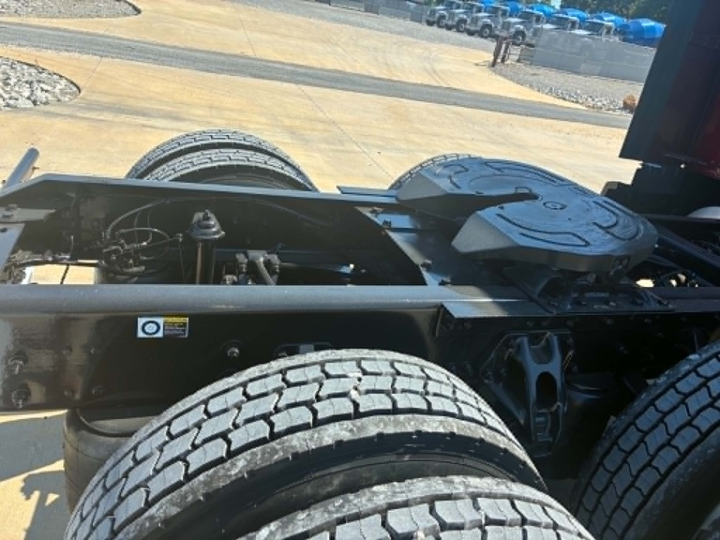 Kenworth T680 chassis view showing dual rear axles and frame; visible components include suspension air lines, drive shaft area, and mounting brackets.