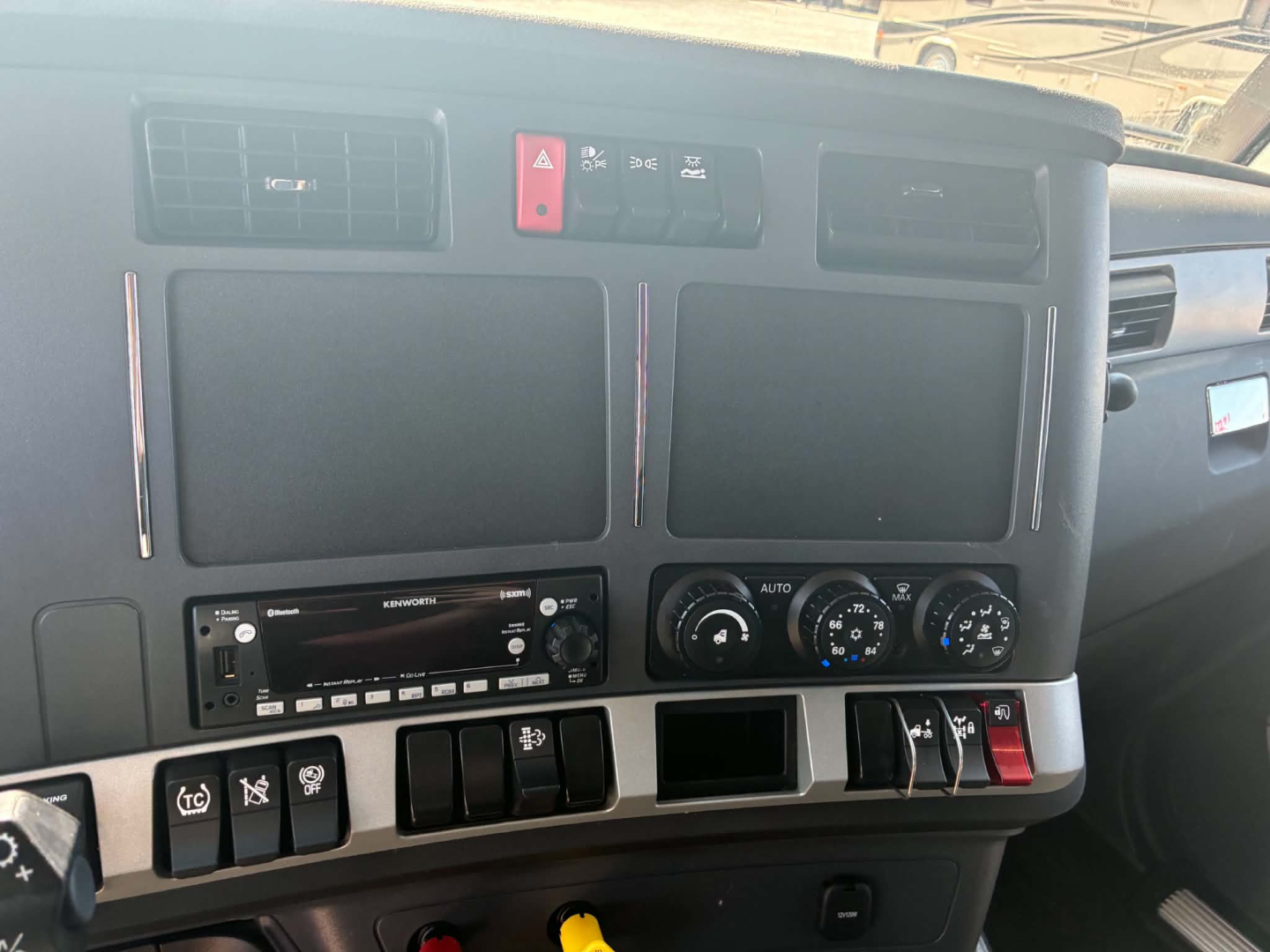 Kenworth T680 dash panel with two large blank displays, climate controls, switches, and a stereo head unit visible.