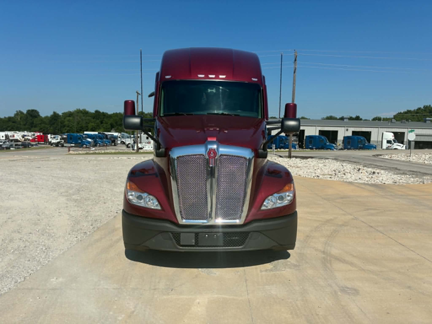 Kenworth T680 truck front view with maroon cab and chrome grille, large bumper, headlights, and side mirrors.
