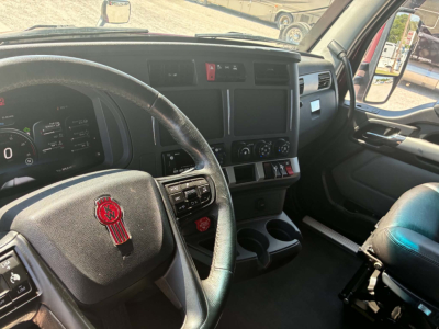 Kenworth T680 cabin interior showing driver’s seat and steering wheel with Kenworth emblem and dashboard controls.