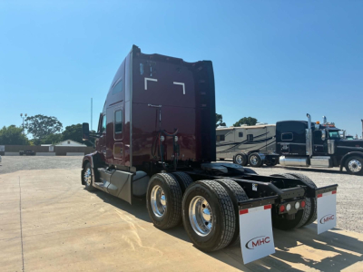 Kenworth T680 semi-truck in view showing rear and side, nozzle, dual rear axles, maroon cab, chrome wheels, mudflaps with MHC logo.
